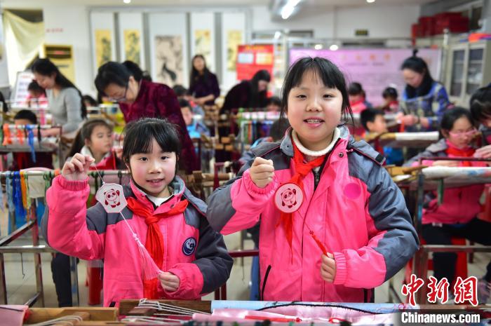 圖為小學(xué)生展示繡制好的2022年北京冬奧會吉祥物“冰墩墩”形象?！∮髟屏?攝