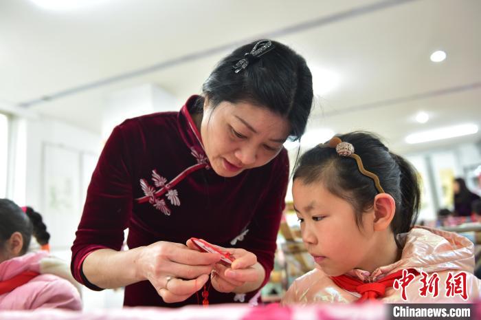 江西省級非遺豫章繡傳承人手把手指導(dǎo)小學(xué)生繡制2022年北京冬奧會吉祥物“冰墩墩”形象。　喻云亮 攝