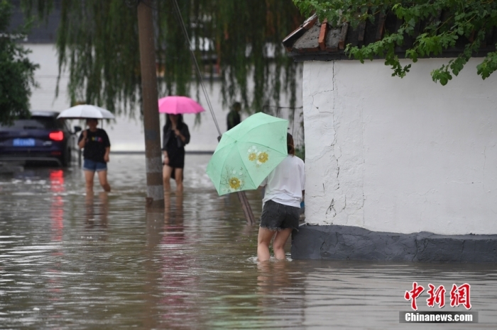 7月31日，市民行走在雨中的北京房山區(qū)瓦窯頭村。北京市氣象臺(tái)當(dāng)日10時(shí)發(fā)布分區(qū)域暴雨紅色預(yù)警信號(hào)。北京市水文總站發(fā)布洪水紅色預(yù)警，預(yù)計(jì)當(dāng)日12時(shí)至14時(shí)，房山區(qū)大石河流域?qū)⒊霈F(xiàn)紅色預(yù)警標(biāo)準(zhǔn)洪水。<a target='_blank' href='/'><p  align=