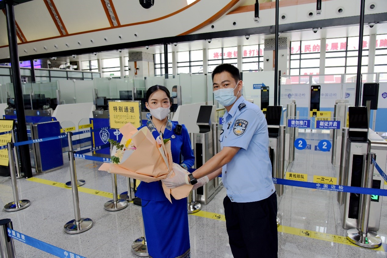 磨憨出入境邊防檢查站民警為中老鐵路第100萬(wàn)名出入境旅客，D888次國(guó)際旅客列車(chē)?yán)蠐爰藙?wù)員森達(dá)拉·妮緹婭（Sengdala Nitiya），送上鮮花。黃遠(yuǎn)飛 攝