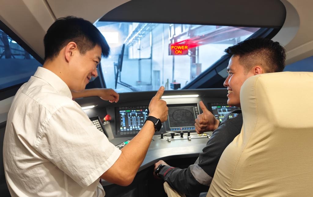 8月25日，在印度尼西亞萬隆的雅萬高鐵德卡魯爾動車所內(nèi)，中國師傅穆振（左）在向印尼火車司機塞蒂亞萬講解動車組出庫前的上電作業(yè)。