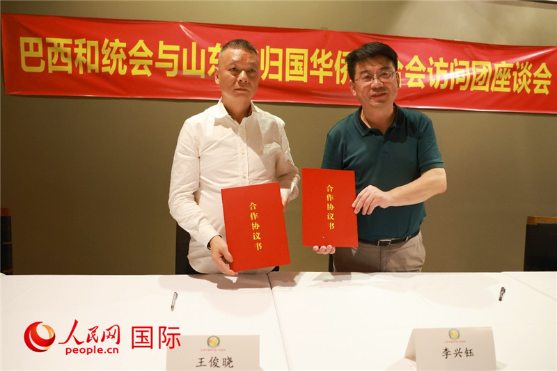 中國僑聯(lián)副主席、山東省僑聯(lián)主席李興鈺（右）與巴西和統(tǒng)會會長王俊曉簽署合作協(xié)議書。人民網(wǎng)記者 陳海琪攝