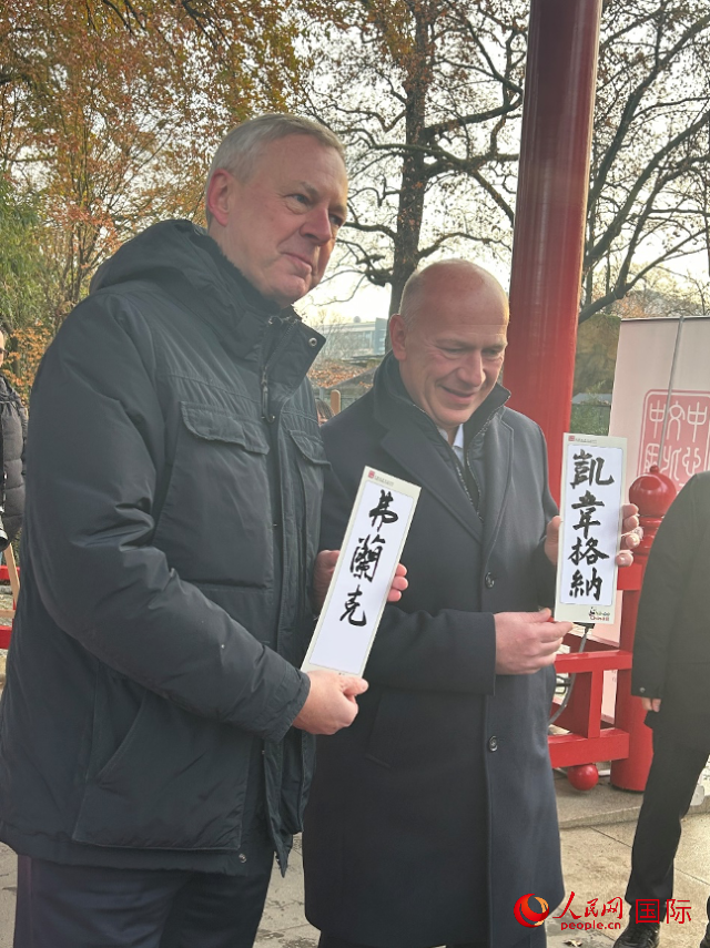 柏林市長韋格納（右）、動物園監(jiān)事會主席布魯克曼（左）手持中國文化中心工作人員現(xiàn)場手書的中文名字。人民網(wǎng)記者 徐馨攝