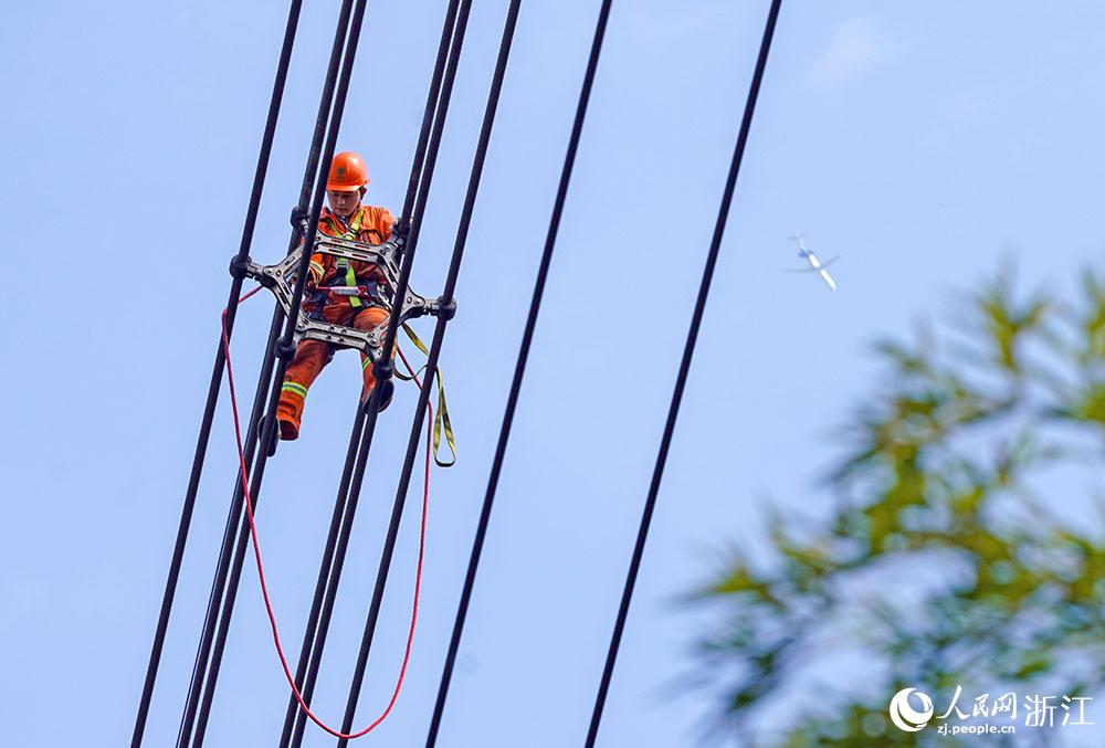 3月11日，在浙江省諸暨市河上鎮(zhèn)，浙江省送變電工程有限公司檢修人員在高空的導(dǎo)線上進(jìn)行線路檢修維護(hù)。人民網(wǎng) 章勇濤攝