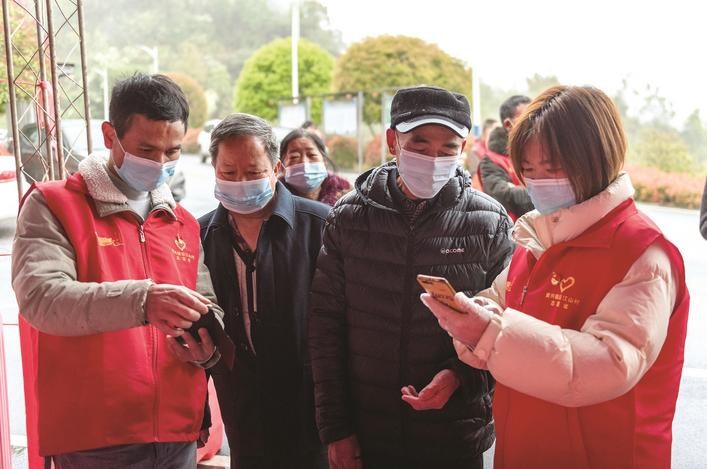長(zhǎng)沙縣黨員志愿者正在幫助參與核酸檢測(cè)的群眾掃描“場(chǎng)所碼”。劉思源 攝