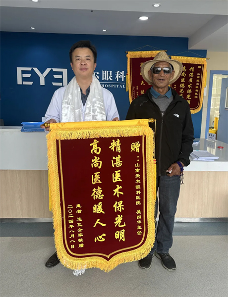 達(dá)瓦老人向吳四華（左）贈送錦旗。受訪者供圖