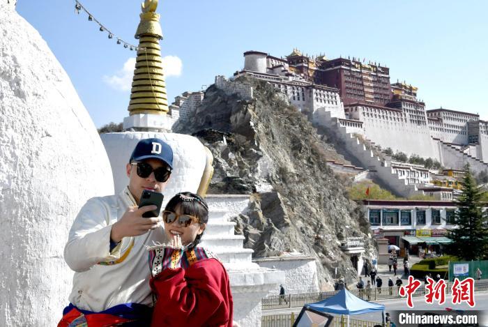 4月17日，游客身著藏式元素服裝在拉薩布達拉宮觀景臺拍照留念。　李林 攝