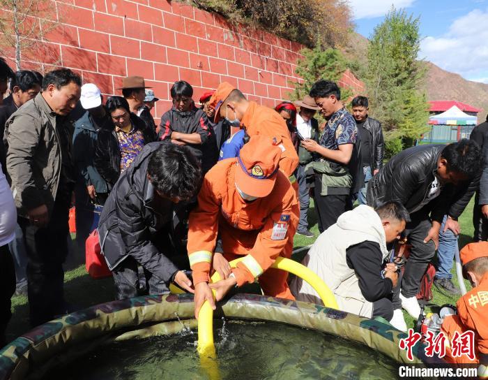 圖為森林消防員為護(hù)林員講解滅火裝備的使用方法?！〔际猩窒乐ш?供圖