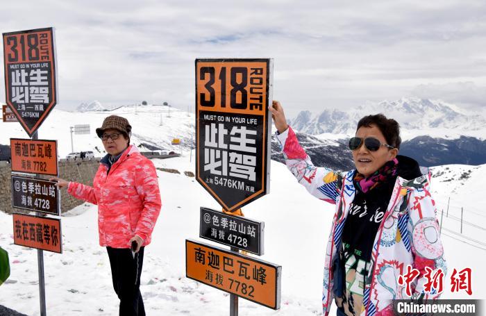 圖為5月14日，西藏林芝色季拉山觀景臺，游客與南迦巴瓦峰合影?！±盍?攝