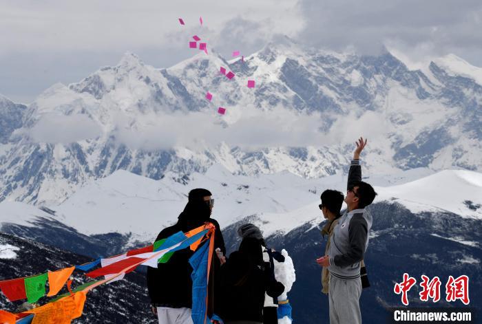 圖為5月14日，游客在西藏林芝色季拉山觀景臺拋灑“隆達”(風馬旗，藏族民眾的一種祈福方式)?！±盍?攝