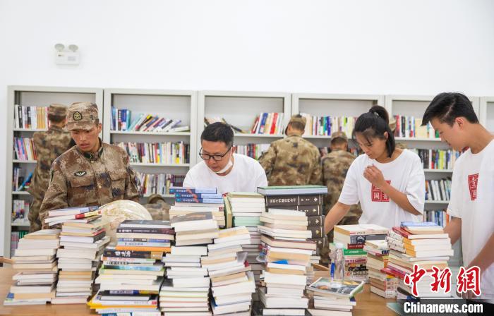 圖為志愿者們和邊防戰(zhàn)士整理圖書?！詵| 攝
