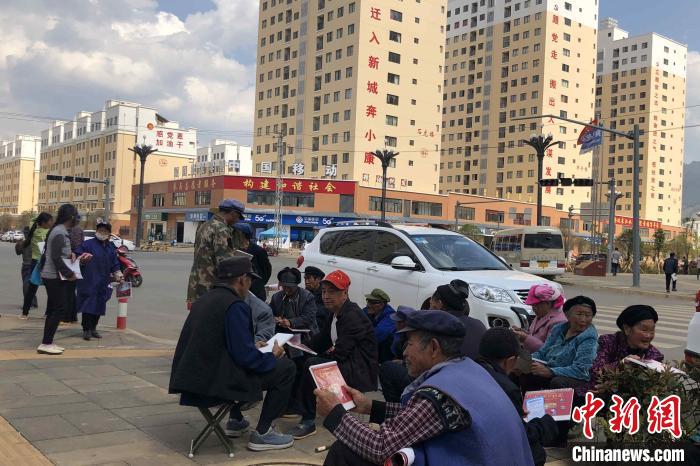 圖為會澤縣城易地扶貧搬遷安置點內(nèi)，老人們聚在廣場上聊天，身后是他們的新家?！】姵?攝