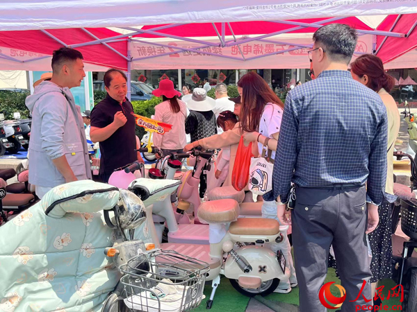 某電動(dòng)自行車品牌工作人員向消費(fèi)者介紹以舊換新相關(guān)情況。人民網(wǎng)記者 杜燕飛攝