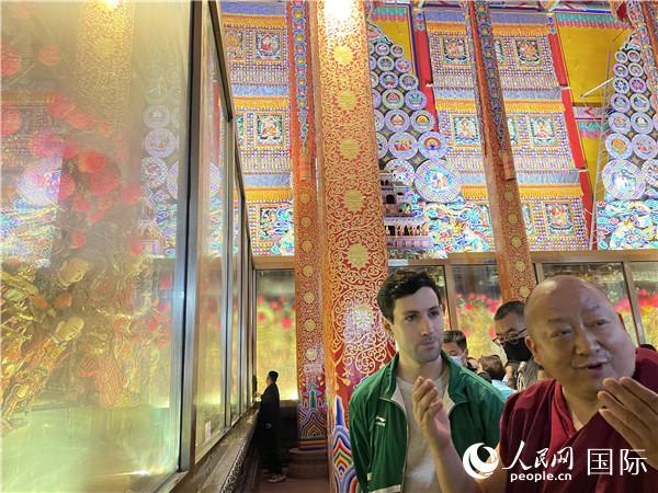 7月25日，省級非物質(zhì)文化遺產(chǎn)項目塔爾寺酥油花的代表性傳承人朋措堅參（右）在塔爾寺酥油花館講解酥油花的制作過程。人民網(wǎng) 謝瑩攝