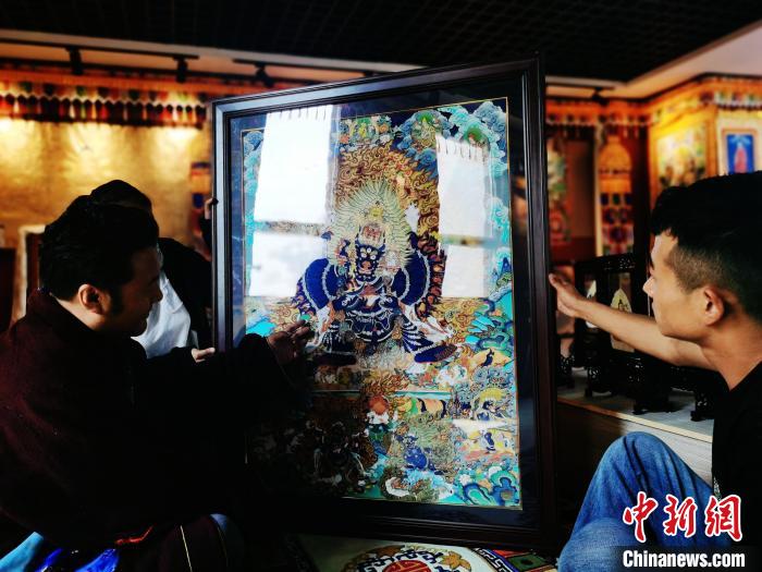 圖為久美尖措(左)與徒弟們展示唐卡作品?！?zhí)砀?攝