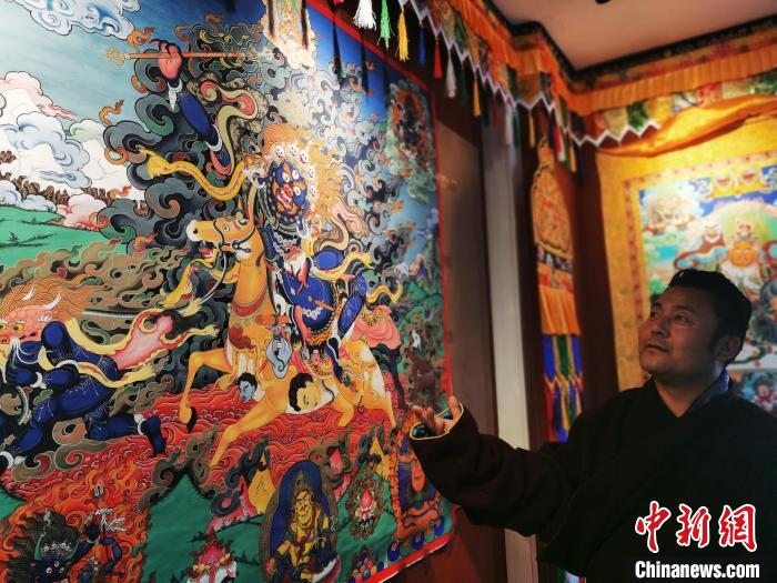 圖為久美尖措展示唐卡作品?！?zhí)砀?攝