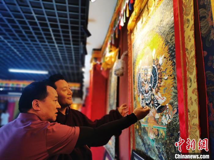 圖為久美尖措展示唐卡作品?！?zhí)砀?攝