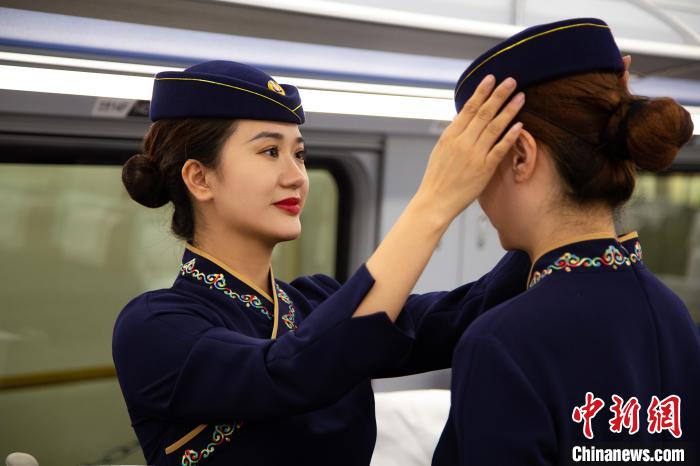 圖為青藏鐵路西格段“復(fù)興號(hào)”動(dòng)車組乘務(wù)員互相整理新制服。　李磊 攝