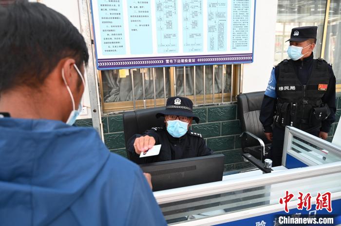 圖為移民管理警察登記完身份信息后將證件歸還給行人?！≮w朗 攝