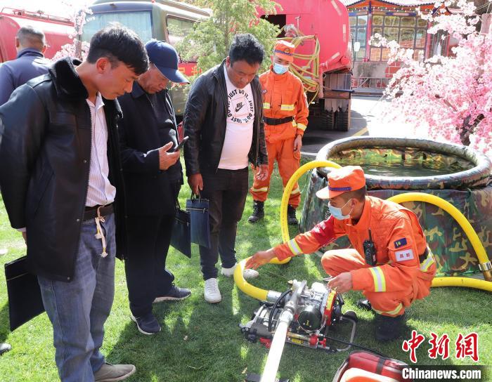 圖為森林消防員為護(hù)林員講解滅火裝備的使用方法?！〔际猩窒乐ш?duì) 供圖