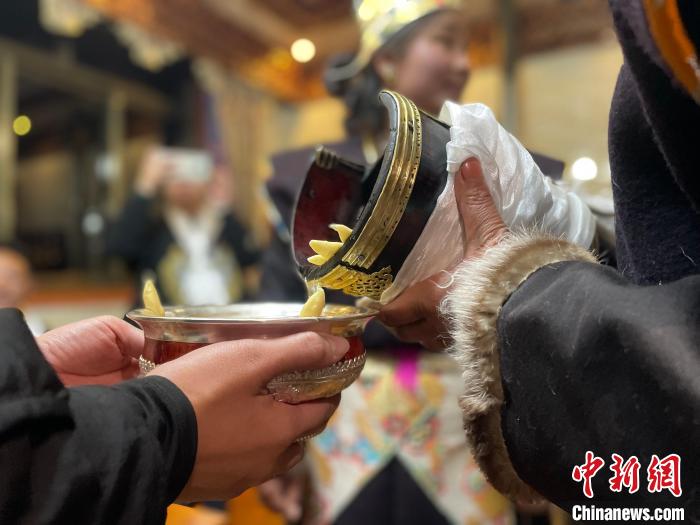 圖為主人在碗中斟滿青稞酒?！∪轿木?攝